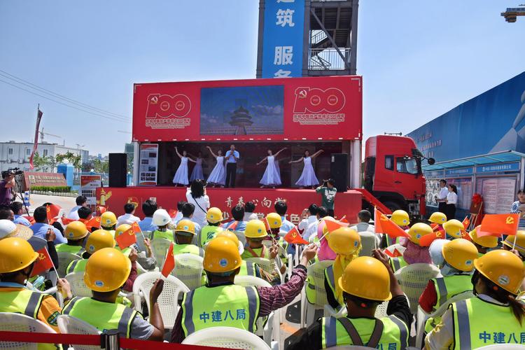 6月19日,建筑工人观看红色大篷车上的文艺表演.